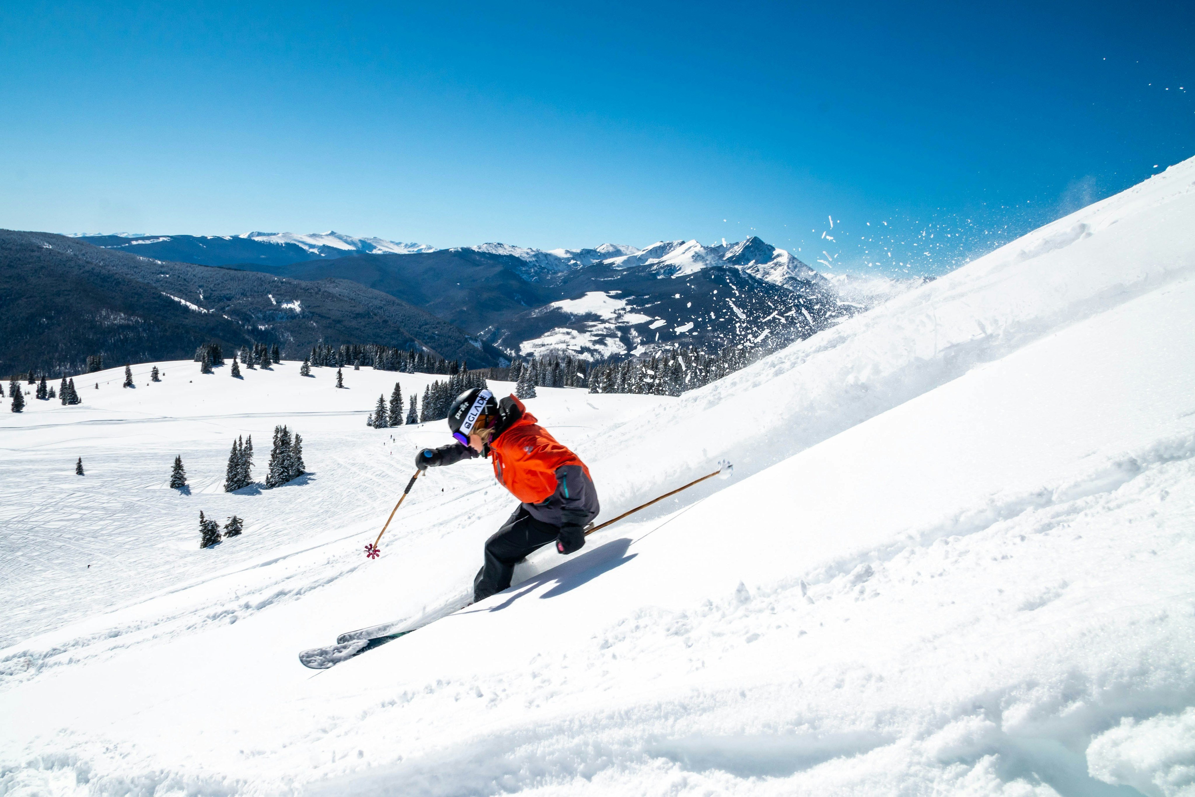 Skier carving fresh powder on a sunny Vail run