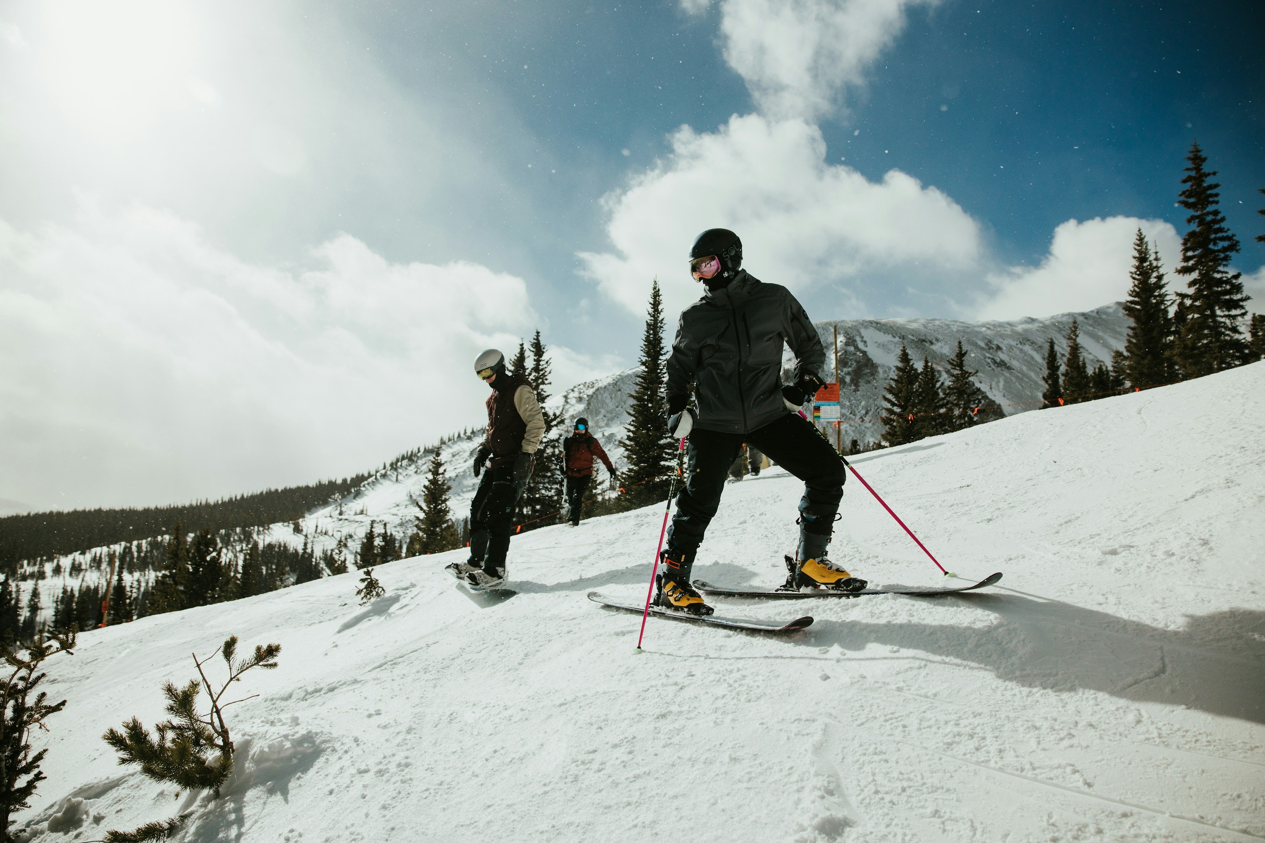Two skiers climbing a snowy slope in bright sun