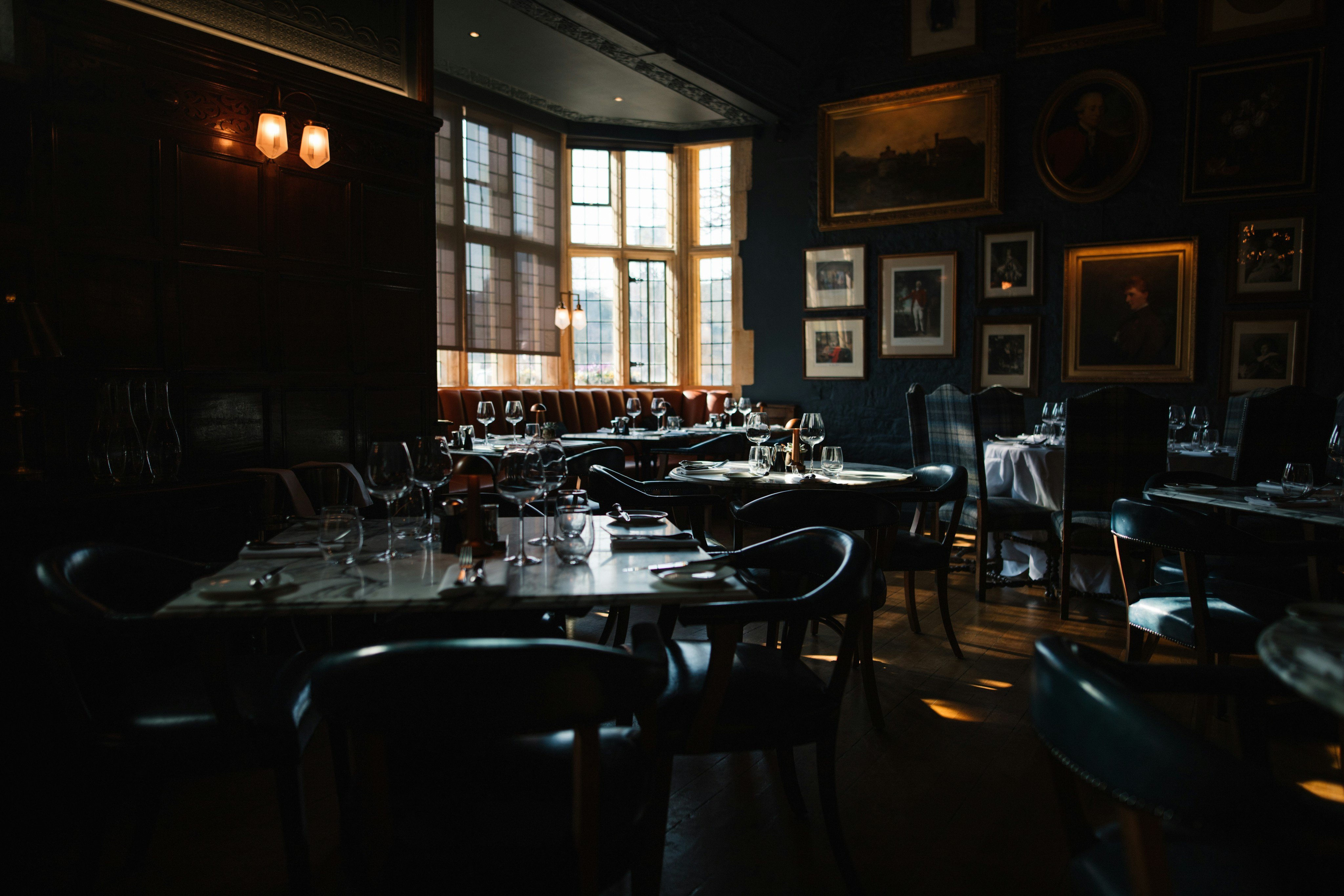 Moody dark-paneled brasserie dining room with framed art